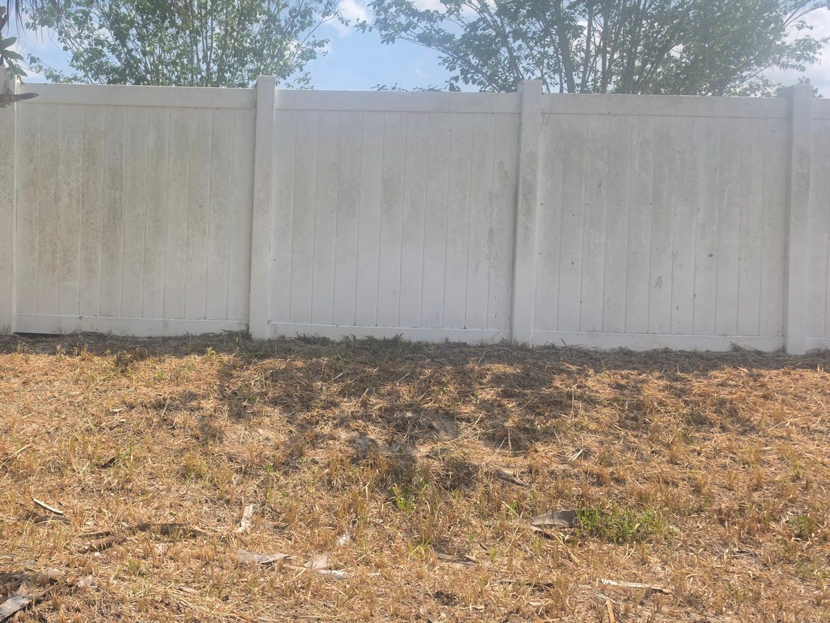 Dirty vinyl fence with algae and mildew before pressure washing