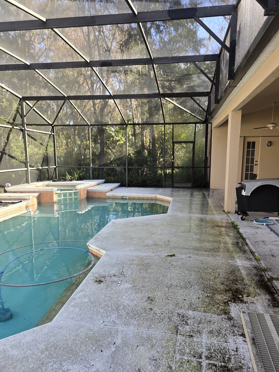 Screen-enclosed pool cage in Central Florida before cleaning, with algae and mildew on the deck and frame